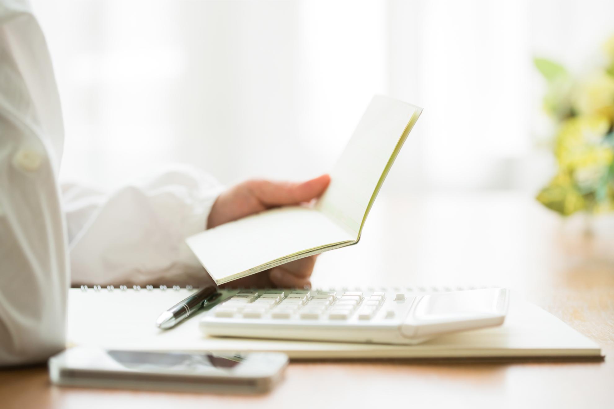 通帳と電卓で計算している様子