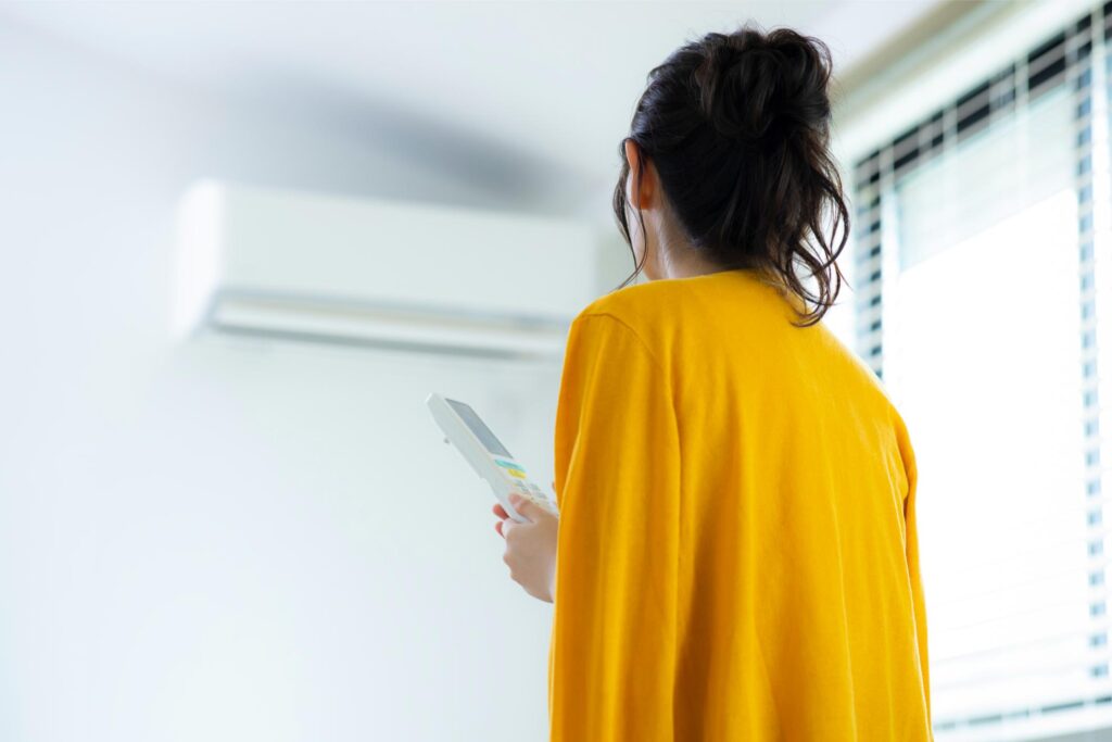 エアコンのリモコンを操作している女性