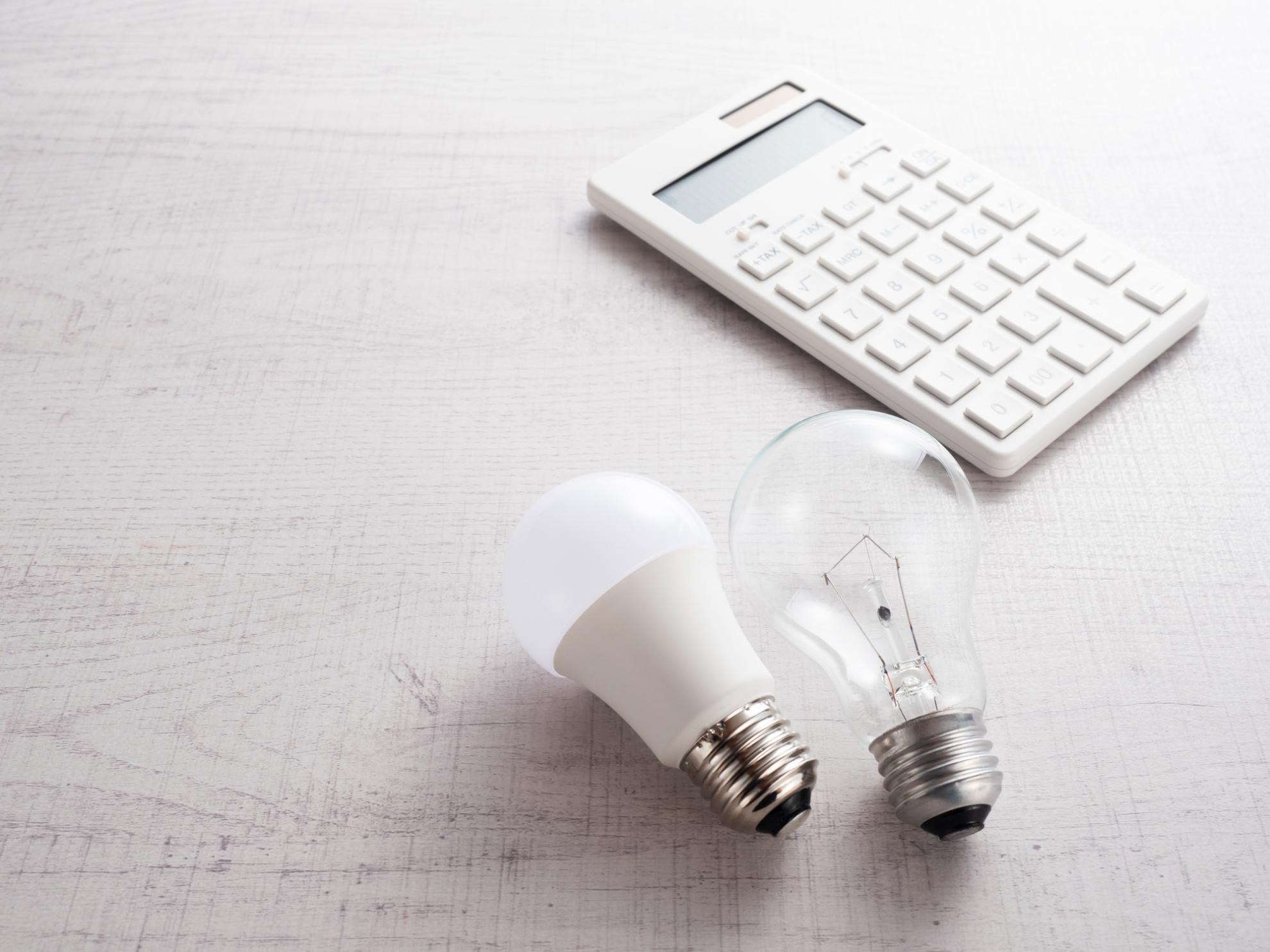電気代の比較や計算をイメージさせる、並べられたLED電球と白熱電球、電卓