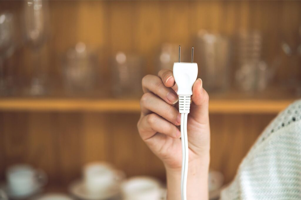 待機電力を減らすためにコンセントから抜かれた白い電源プラグ