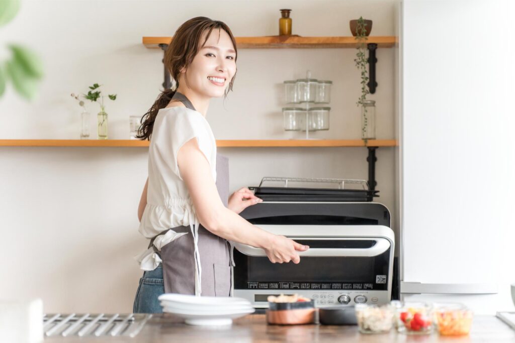 笑顔でオーブンを操作する女性